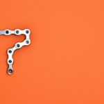 Artistic arrangement of bicycle chain shaped like number seven on orange background.