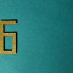 A golden number six on a teal background, perfect for decorative purposes.