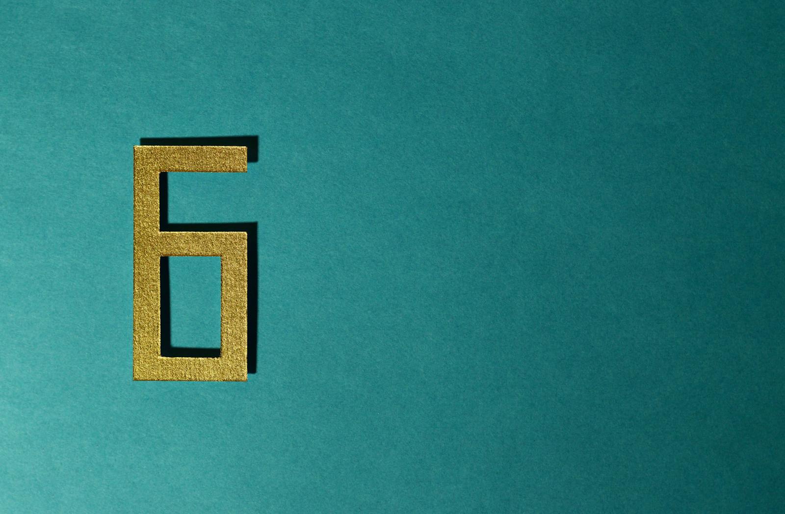 A golden number six on a teal background, perfect for decorative purposes.