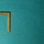 Minimalist image of a golden numeral seven on a teal background, ideal for decorative use.